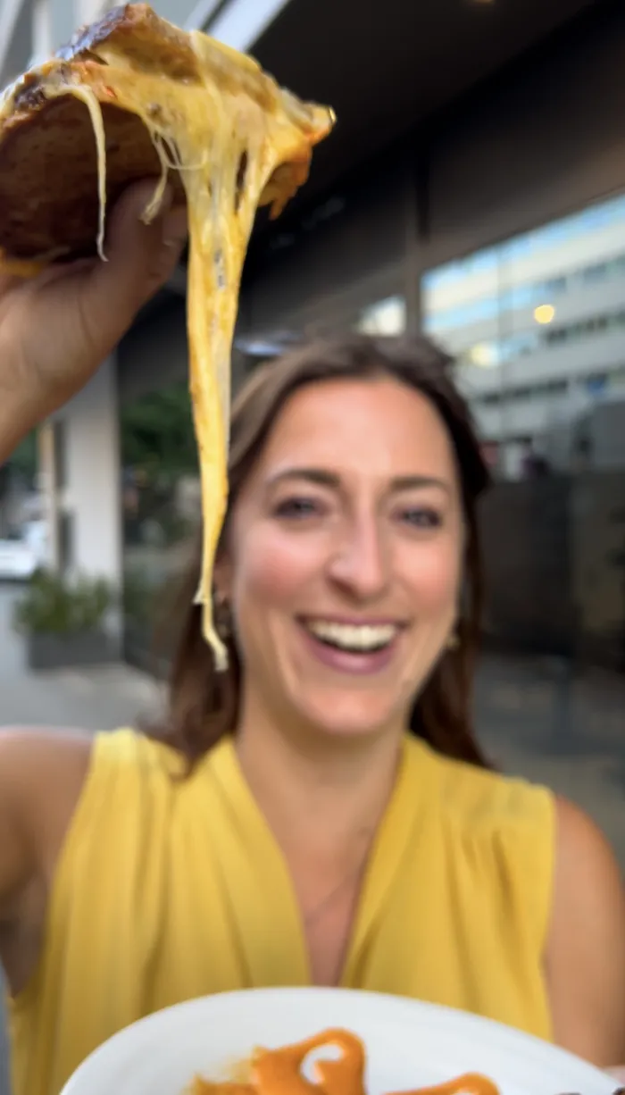 Hannah lacht, während sich der geschmolzene Käse aus ihrem Grilled Cheese zieht