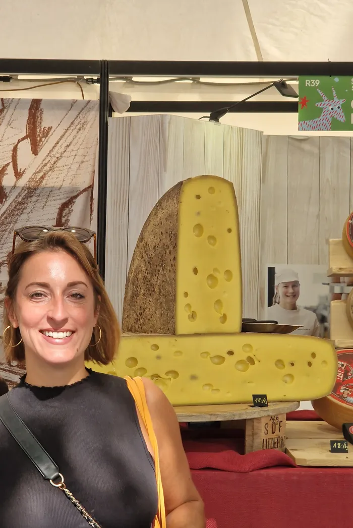 Hannah vor einem großen Laib Käse auf einer Käsemesse in Italien