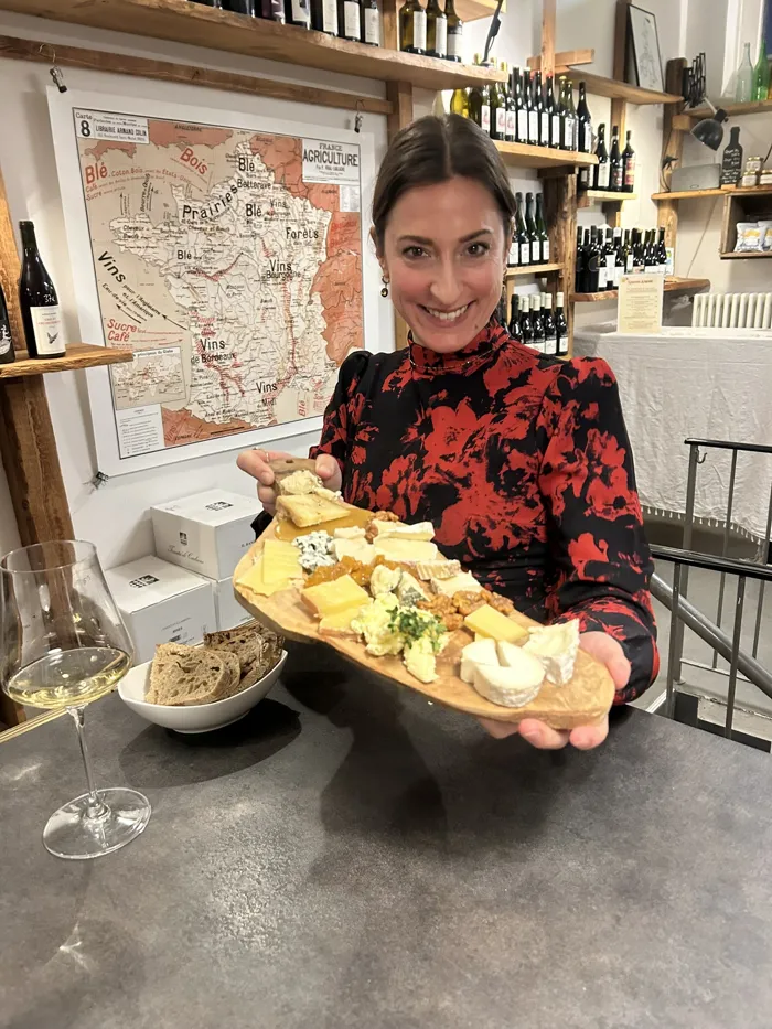 Hannah hält eine Käseplatte vor einer Karte der französischen Weinregionen